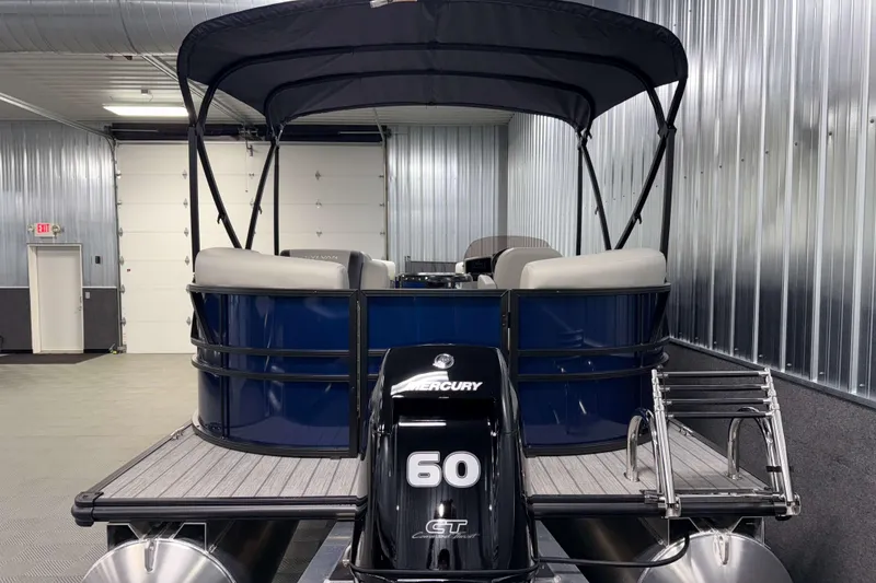 Slide: The Image of 2026 Sylvan Mirage 820 LZ pontoon boat with Mercury 60 engine in a metal-walled garage. - 22