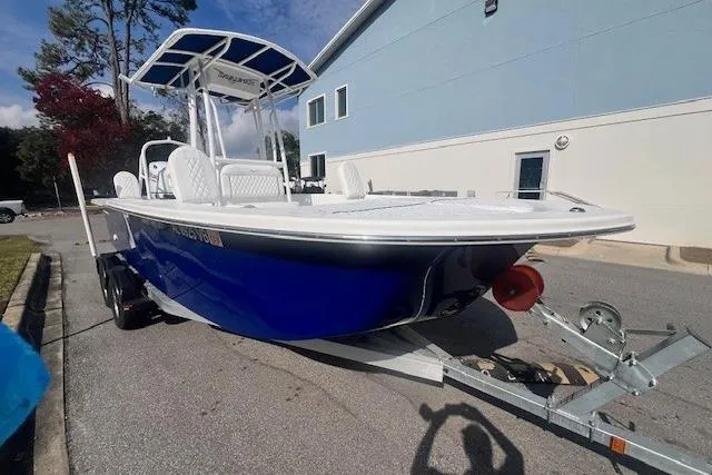 Slide: The Image of 2024 Savannah SS21 boat on trailer, blue hull, parked near a building. - 1
