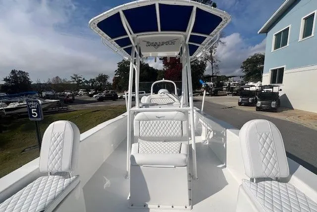Slide: The Image of 2024 Savannah SS21 boat with white seating and blue canopy, docked near a marina. - 15