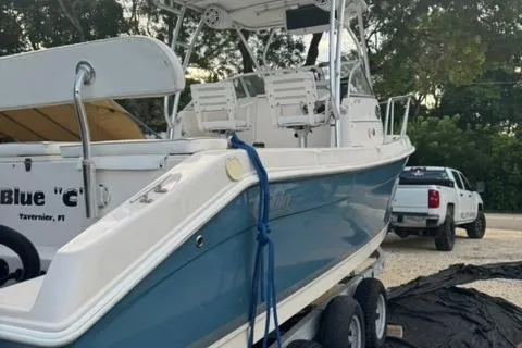 Slide: The Image of 2007 Cobia 270 boat on trailer, parked outdoors with trees and a truck in the background. - 2