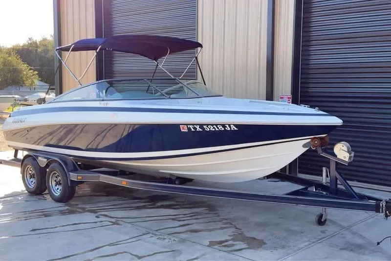 Slide: The Image of 1998 Cobalt 220 boat on trailer, parked outside a garage. - 4