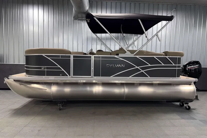 Slide: The Image of 2026 Sylvan Mirage 8520 Cruise pontoon boat in showroom, featuring sleek design and Mercury engine. - 21