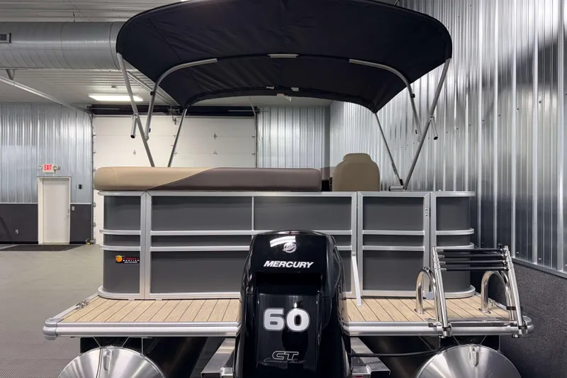 Slide: The Image of 2026 Sylvan Mirage 8520 Cruise pontoon boat with Mercury 60 engine in a metal-walled showroom. - 24