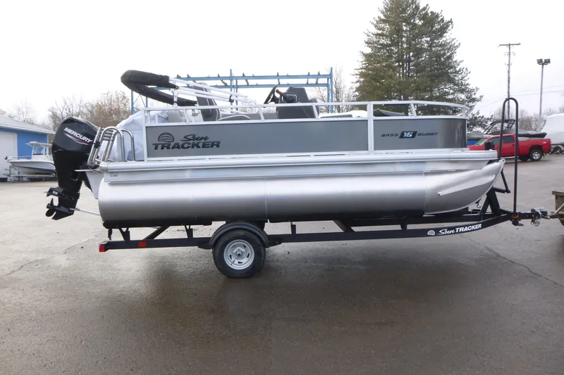 The Image of 2026 Sun Tracker Bass Buggy 16 XL Select pontoon boat on trailer in outdoor setting. - 1