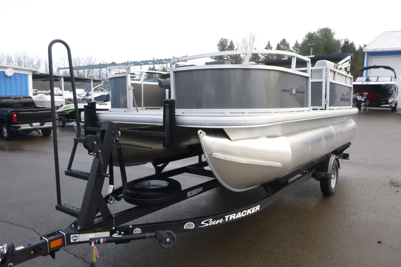 Slide: The Image of 2026 Sun Tracker Bass Buggy 16 XL Select pontoon boat on trailer in marina. - 4