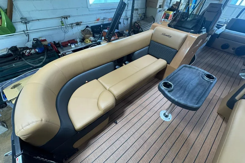 Slide: The Image of 2026 Bentley Pontoons Elite 253 Swingback interior with tan seating and table. - 16