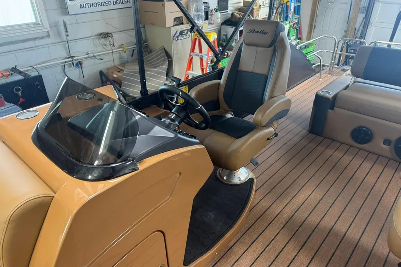 Slide: The Image of 2026 Bentley Pontoons Elite 253 Swingback interior with captain's chair and dashboard. - 17