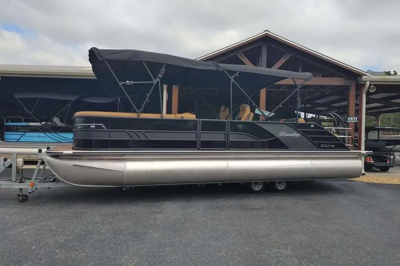Slide: The Image of 2026 Bentley Pontoons Elite 253 Swingback pontoon boat with canopy, parked on a trailer. - 18