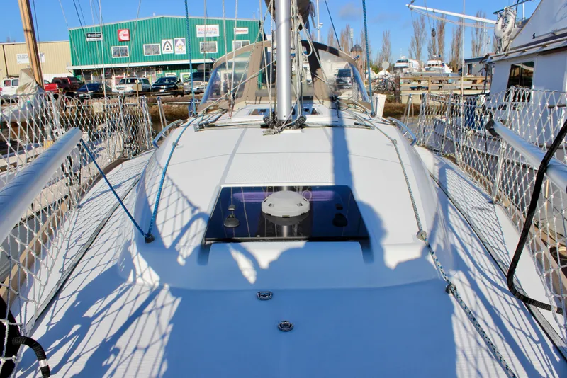 Slide: The Image of 2015 Jeanneau Sun Odyssey 349 sailboat deck with netted railings and marina background. - 14