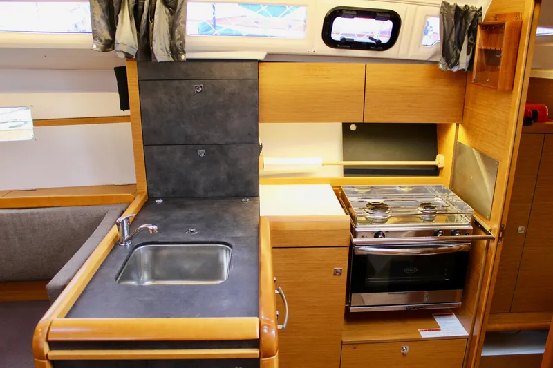 Slide: The Image of Interior of 2015 Jeanneau Sun Odyssey 349 yacht, featuring a compact kitchen with sink and stove. - 31