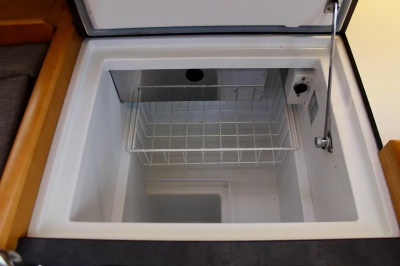 Slide: The Image of Interior view of Jeanneau Sun Odyssey 349's refrigerator, showcasing storage space and wire basket. - 34