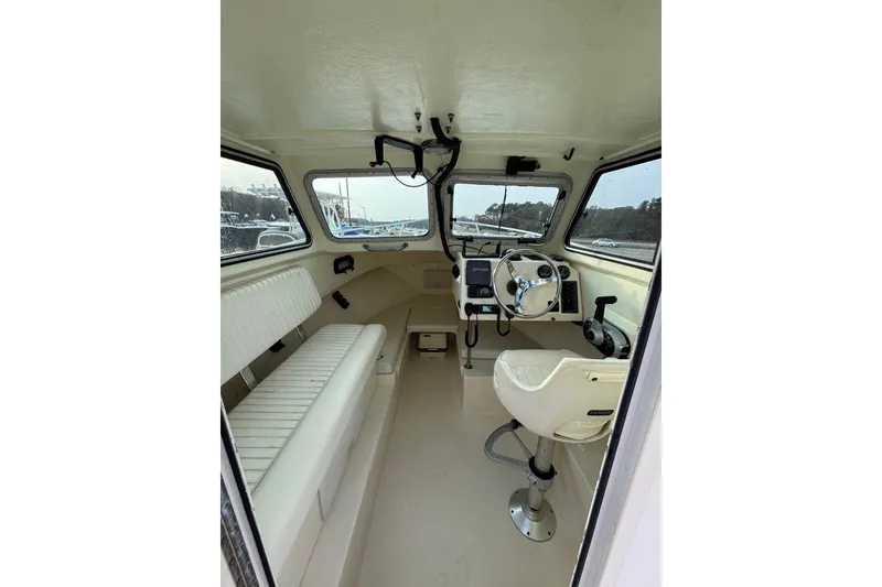 Slide: The Image of Interior of a 2004 Parker 2120 Sport Cabin boat, featuring helm and seating. - 5
