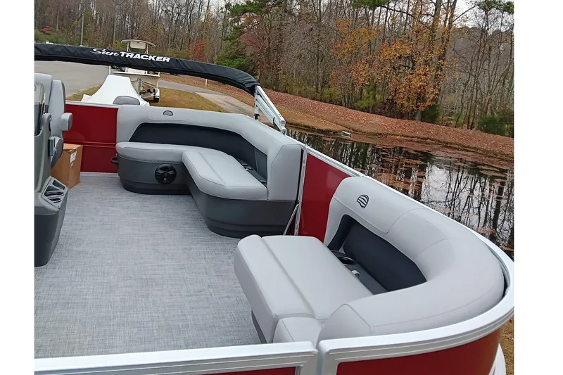 Slide: The Image of 2026 Sun Tracker Party Barge 16 DLX pontoon boat with gray seating, docked by a lake. - 11