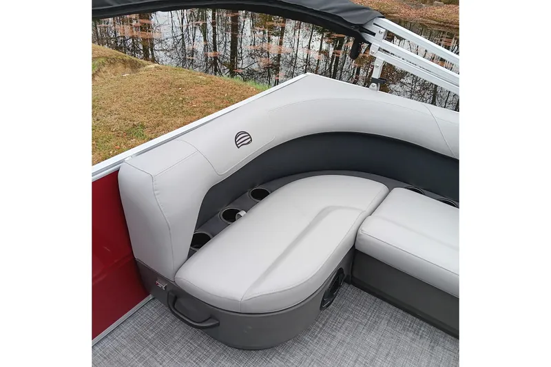 Slide: The Image of 2026 Sun Tracker Party Barge 16 DLX interior seating with cup holders, near water. - 20