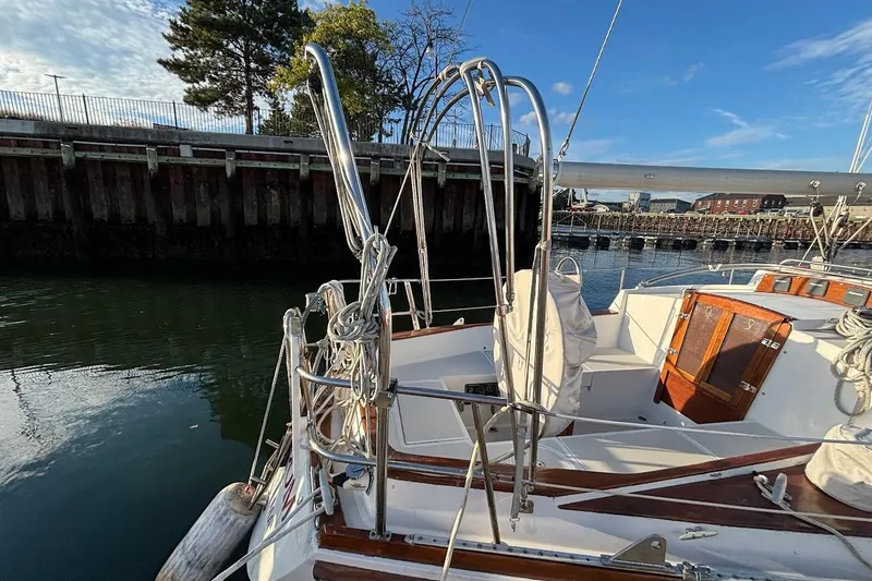 Slide: The Image of 1983 Bristol 38.8 sailboat docked, featuring polished metal railings and wooden accents. - 4