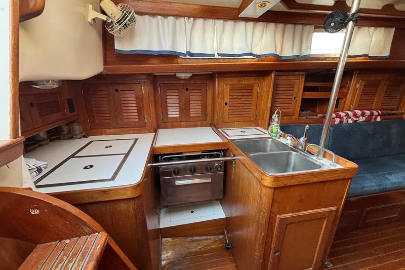 Slide: The Image of 1983 Bristol 38.8 yacht interior with wooden cabinetry and compact kitchen area. - 5