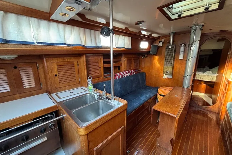 Slide: The Image of 1983 Bristol 38.8 yacht interior with wooden cabinetry, kitchen, and seating area. - 6