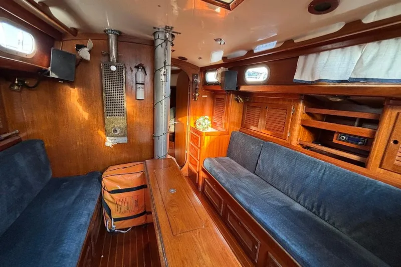 Slide: The Image of Interior of a 1983 Bristol 38.8 sailboat with wooden furnishings and blue seating. - 8
