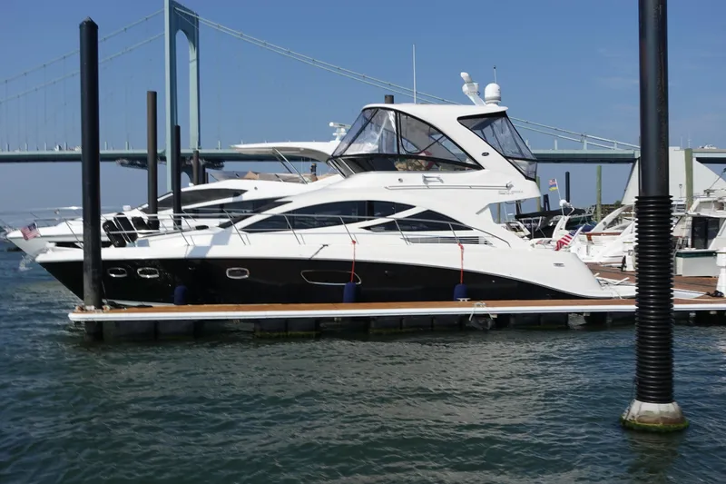 Slide: The Image of 2012 Sea Ray 450 Sedan Bridge yacht docked near a bridge on a sunny day. - 2