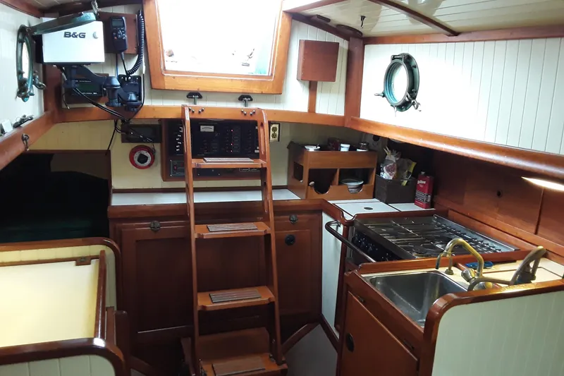Slide: The Image of Interior of a 2000 Sam L. Morse Bristol Channel Cutter 28, featuring a compact galley and navigation equipment. - 2