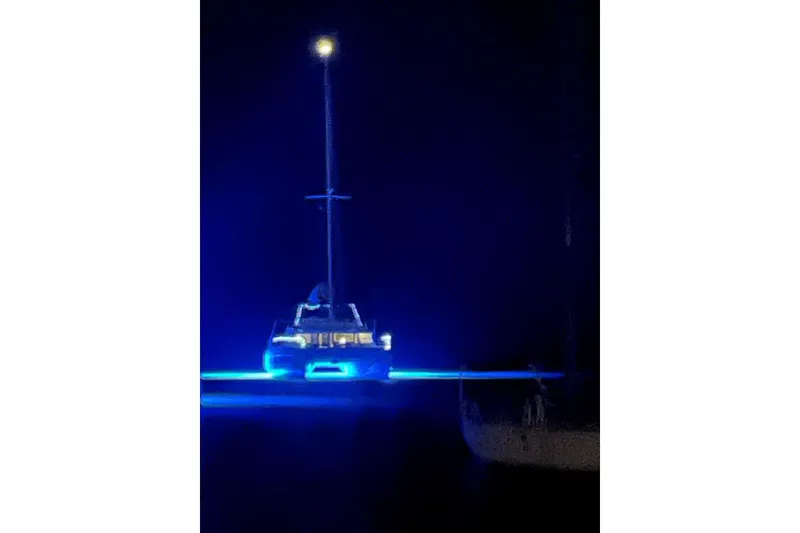 Slide: The Image of Bali 5.4 catamaran illuminated with blue lights at night, 2021 model. - 6