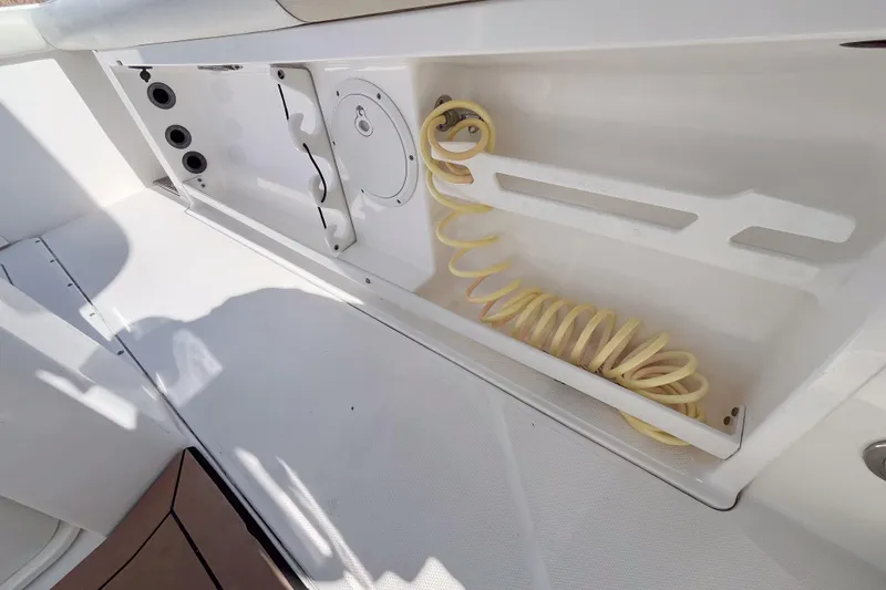 Slide: The Image of Storage compartment with coiled hose on a 2016 Everglades 255 Center Console boat. - 13