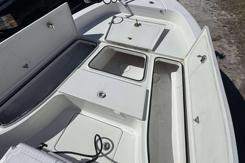 Slide: The Image of 2012 Ranger 2410 Bay Ranger boat with open storage compartments and clean white deck. - 12