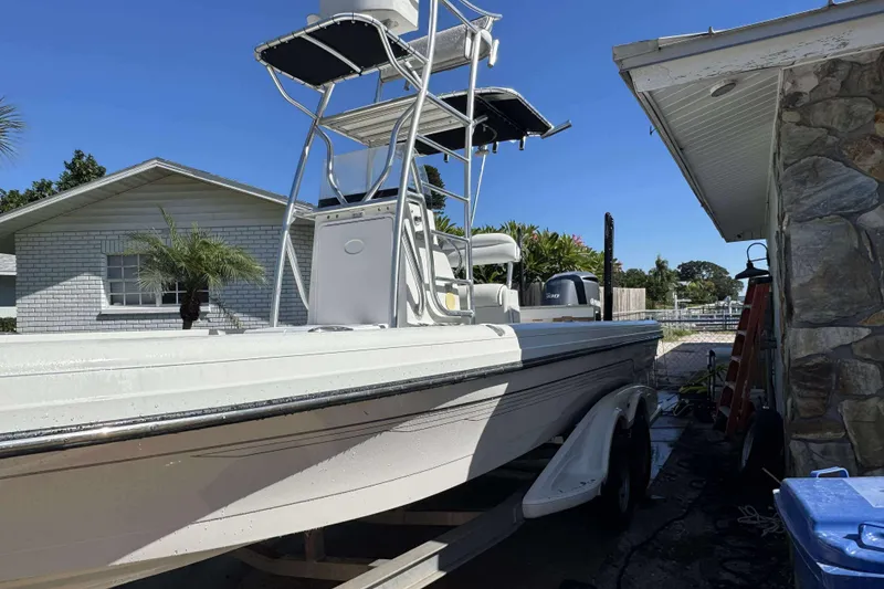 Slide: The Image of 2012 Ranger 2410 Bay Ranger boat on trailer beside house, under clear blue sky. - 13