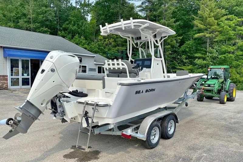 Slide: The Image of 2023 Sea Born LX22 Center Console boat on trailer, parked near a green tractor. - 2