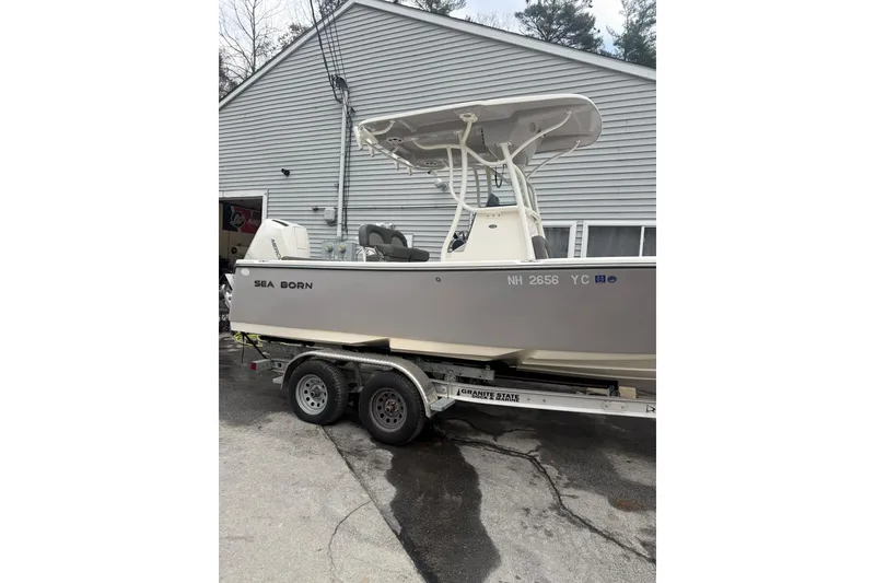 Slide: The Image of 2023 Sea Born LX22 Center Console boat on trailer, parked near a building. - 3