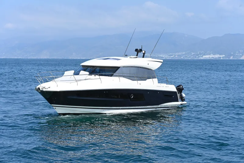 Slide: The Image of 2020 Prestige 460S yacht cruising on calm blue waters with scenic mountain backdrop. - 2