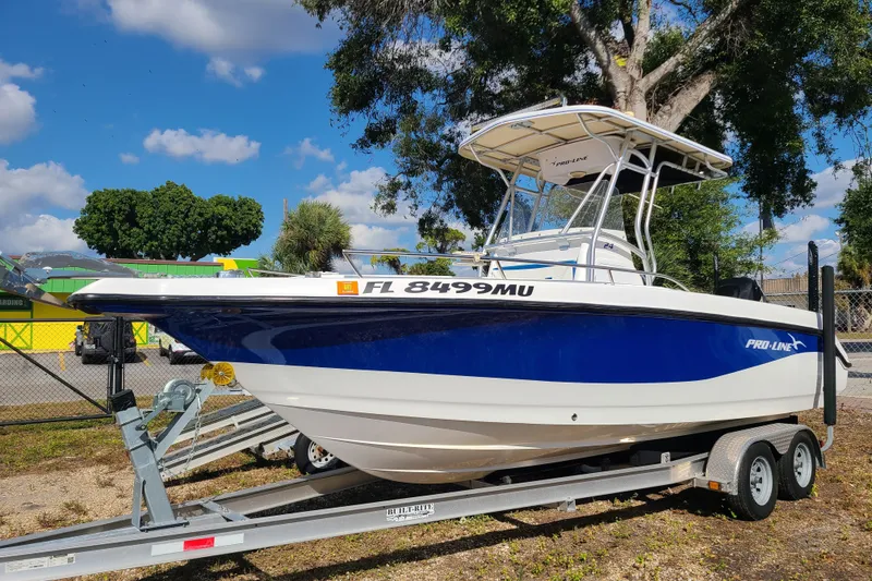 The Image of 2005 Pro-Line 24 Sport boat on trailer, blue and white, parked outdoors. - 0