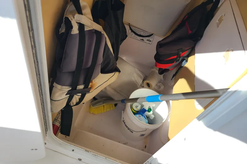 Slide: The Image of Storage compartment of a 2005 Pro-Line 24 Sport boat with cleaning supplies and life jackets. - 12