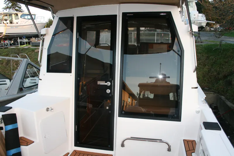 Slide: The Image of 2019 Ranger Tugs R-27 boat exterior with glass door and window, docked outdoors. - 11
