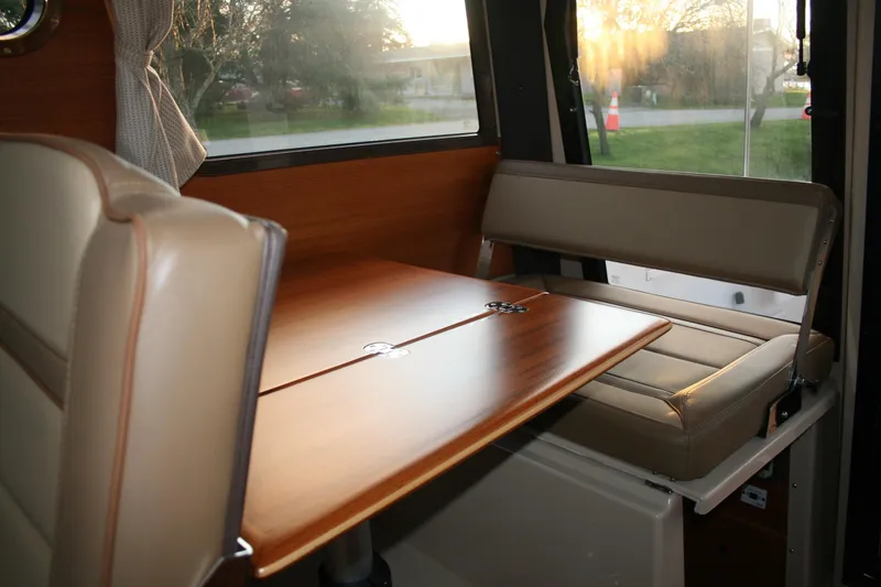 Slide: The Image of Interior of 2019 Ranger Tugs R-27 with wooden table and beige seating. - 6