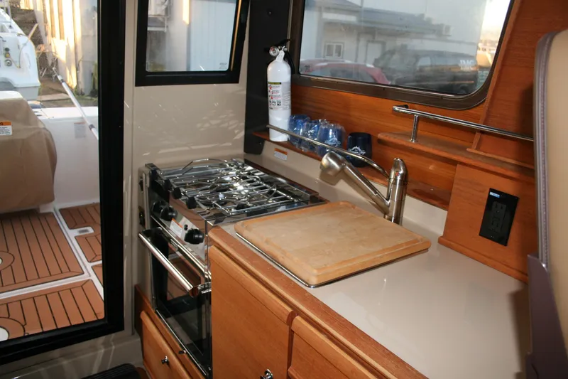 Slide: The Image of 2019 Ranger Tugs R-27 boat kitchen with stove, sink, and cutting board. - 7