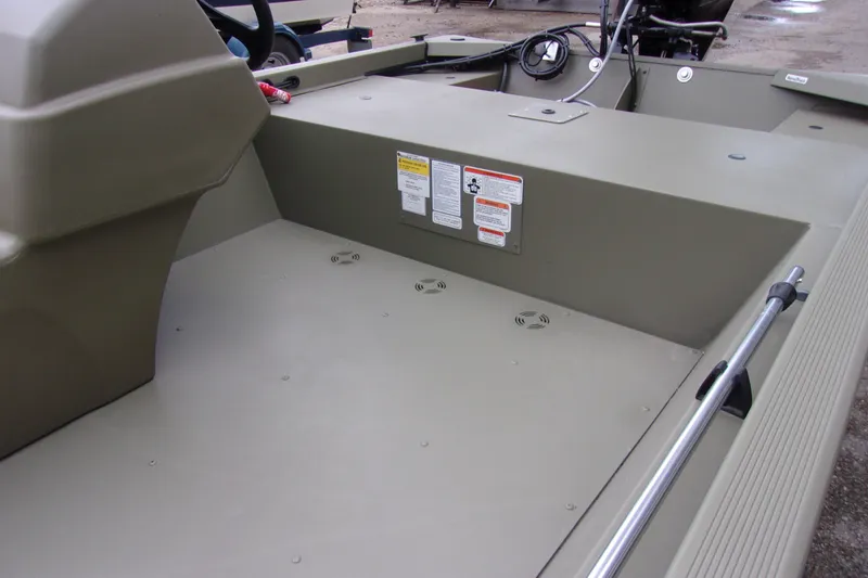 Slide: The Image of 2022 Tracker Grizzly 1648 MVX SC boat interior with steering console and safety labels. - 8