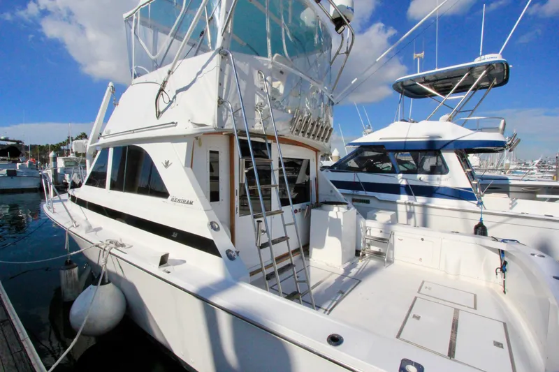 Slide: The Image of 1982 Bertram 35 Flybridge yacht docked at marina under clear blue sky. - 2