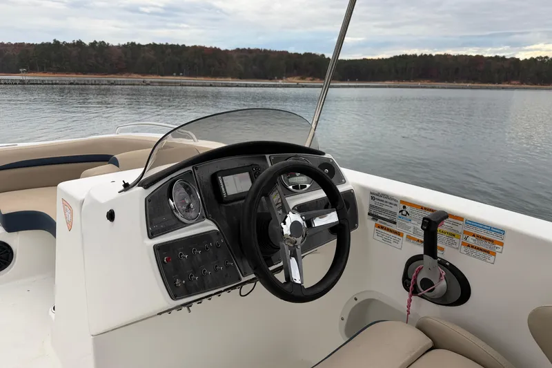 Slide: The Image of 2021 Hurricane SunDeck Sport 192 RL OB boat dashboard with steering wheel on calm water. - 8