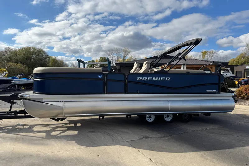 Slide: The Image of 2026 Premier 230 SunSation RF pontoon boat on trailer under a partly cloudy sky. - 3