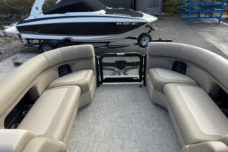 Slide: The Image of 2026 Premier 230 SunSation RF pontoon boat interior with beige seating and a docked speedboat. - 9