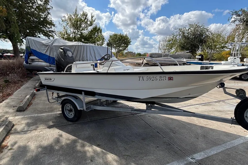 Slide: The Image of 2008 Boston Whaler 150 Sport boat on trailer in parking lot, sunny day. - 11