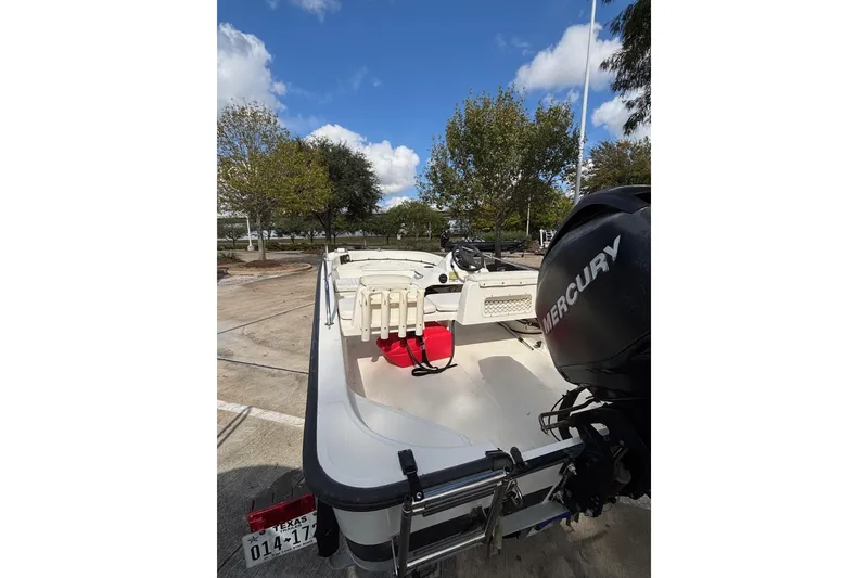 Slide: The Image of 2008 Boston Whaler 150 Sport boat with Mercury engine, parked outdoors under blue sky. - 8