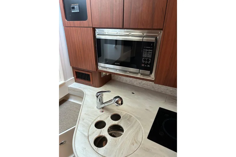 Slide: The Image of 2017 Grady-White Express 330 kitchen with microwave, sink, and wooden cabinetry. - 9