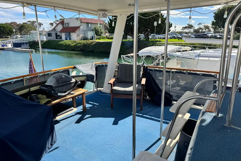 Slide: The Image of 1987 Californian 43 Cockpit MY yacht with spacious outdoor seating and grill, docked by the water. - 5