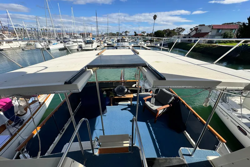 Slide: The Image of 1987 Californian 43 Cockpit MY yacht docked in a marina, featuring spacious deck and seating. - 7