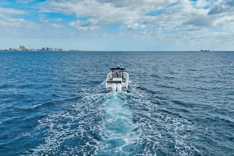 Slide: The Image of SeaWell 345XL boat cruising on open ocean, 2025 model, with city skyline in background. - 3