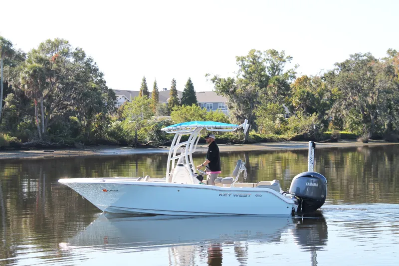 The Image of 2024 Key West 203 FS boat on calm water with lush greenery in the background. - 1