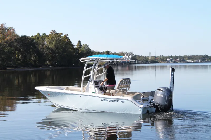 Slide: The Image of 2024 Key West 203 FS boat cruising on a calm lake with trees in the background. - 9