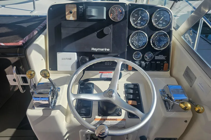 Slide: The Image of 2001 Pursuit 3000 Express boat dashboard with steering wheel and control gauges. - 23